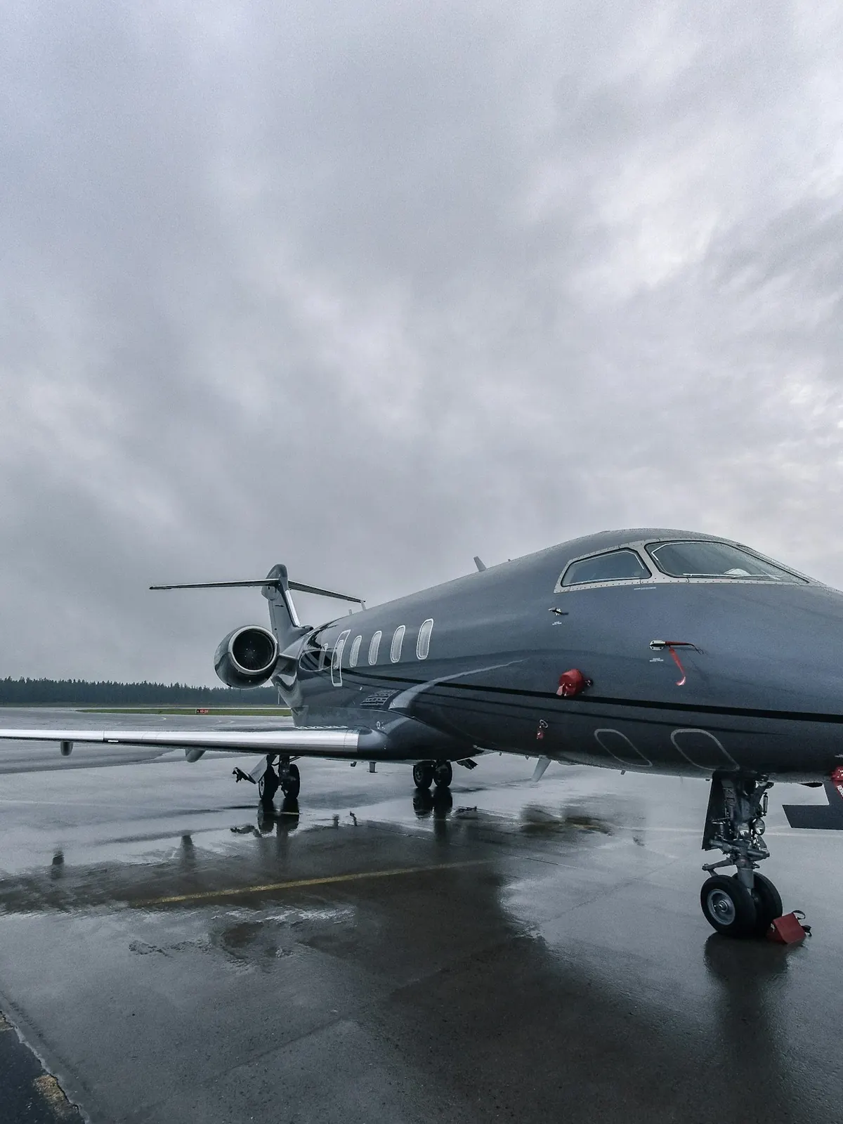 Dark grey business jet on a wet ramp under heavy cloud