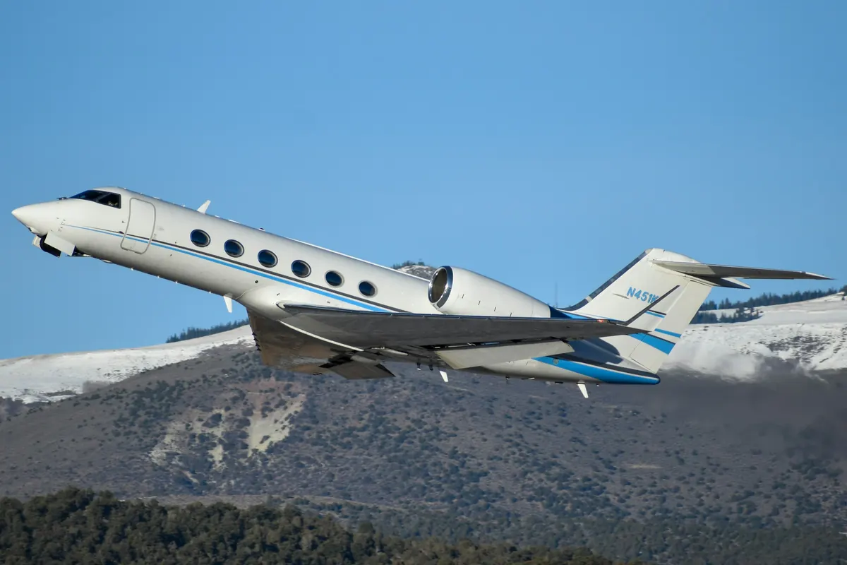 Long range Gulfstream jet climbing past snowy mountains