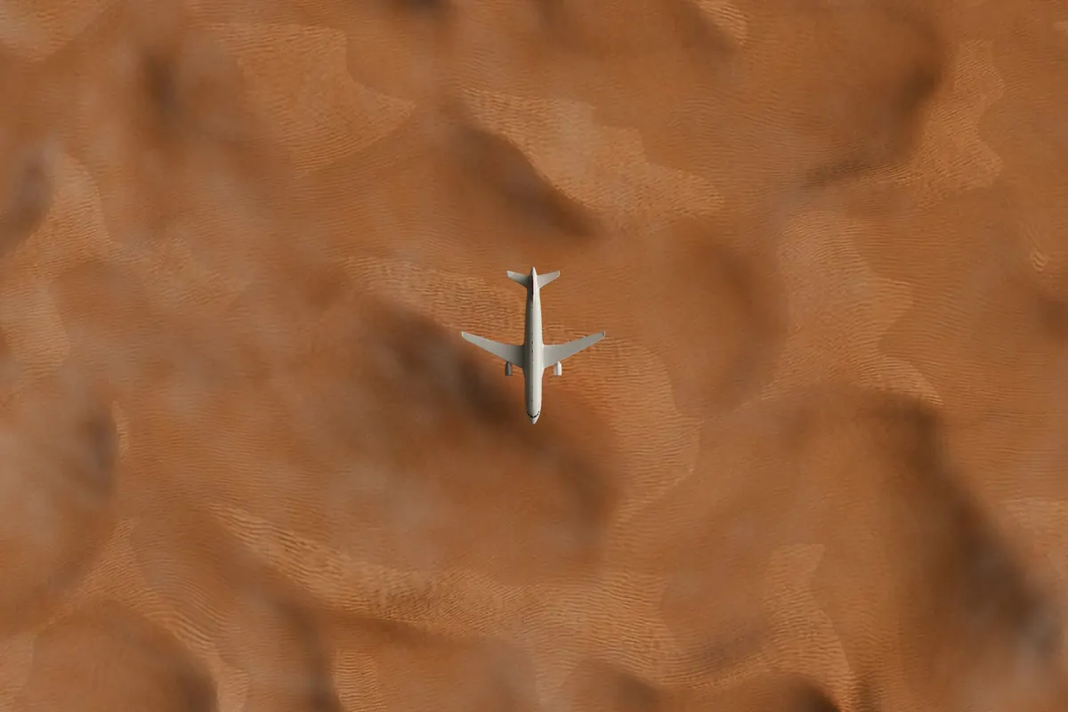 A lone business jet seen from above crossing rippled desert sand