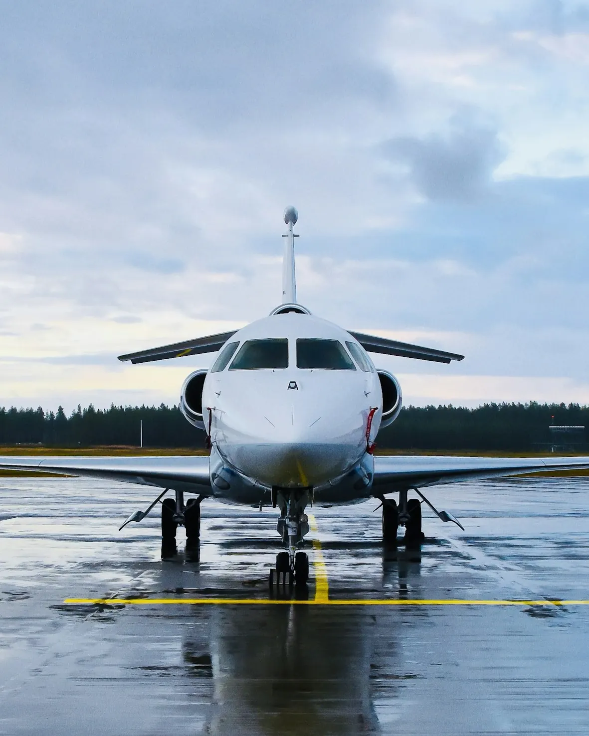 A business jet seen head-on on a wet runway under a pale sky