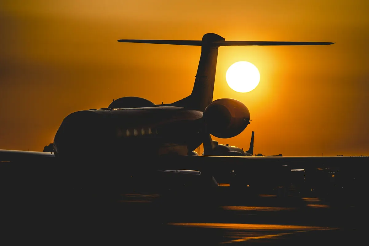 A business jet silhouetted against a low orange sun